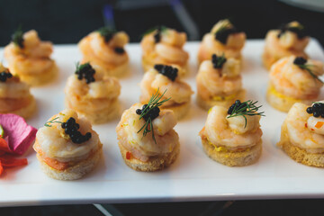 Beautifully decorated banquet catering table, with variety of with different food snacks appetizers on corporate birthday party event or wedding celebration, canape, salad, delicatessen setting