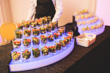 Beautifully decorated banquet catering table, with variety of with different food snacks appetizers on corporate birthday party event or wedding celebration, canape, salad, delicatessen setting