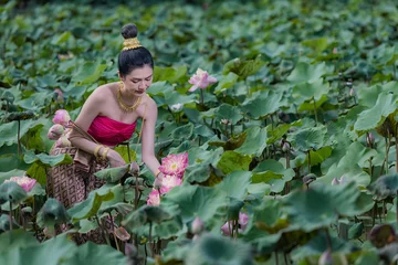 Fotobehang Lotusbloem Beautiful women in Lotus Gardens. Beautiful girl in the lotus field. Asian woman Harvests lotus flowers and she wear Traditional Thai dresses, Thailand  © ENGINEER - STUDIO