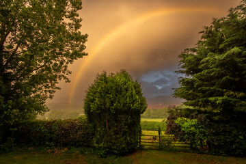 Beautiful Rainbow over a field in the British countryside. Evening view with a misty sky