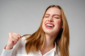 Joyful Young Blonde Woman Smiling against gray background