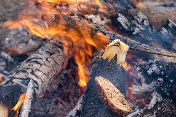 a slice of toasted bread with fried bacon an open fire in nature, slanina,traditional food in Romania