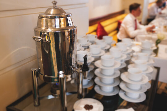 Set of coffee break lunch in the hotel restaurant during conference meeting, with tea and coffee catering, decorated banquet table with white tableware and metal tea maker machine boiler