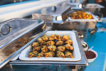 Beautifully decorated catering banquet table with different main course hot food dishes and garnish, with rice, chicken, salmon fish, lamb, vegetables and kebab on party event wedding celebration