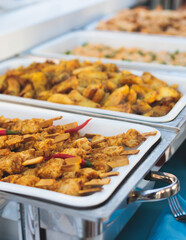 Beautifully decorated catering banquet table with different main course hot food dishes and garnish, with rice, chicken, salmon fish, lamb, vegetables and kebab on party event wedding celebration