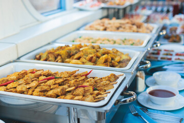Beautifully decorated catering banquet table with different main course hot food dishes and garnish, with rice, chicken, salmon fish, lamb, vegetables and kebab on party event wedding celebration