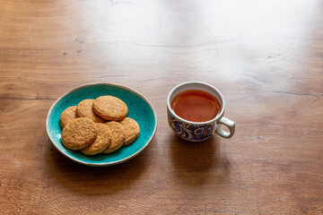 A cup of black tea and some biscuits on a wooden table in perfect details