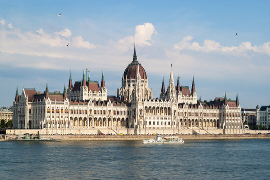 Hungarian parliament building,  tourist boat along the Danube river and flying birds in the sky, Budapest, Hungary.