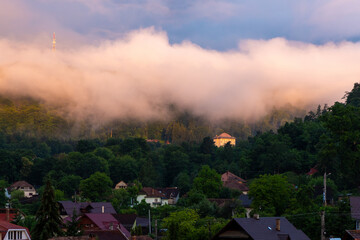 Steam rising over the village after rain. A cloud wave over a mountain village