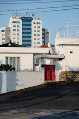 Traditional house with red gate and modern building in the background