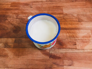 Fresh milk in enamel mug on a wooden cutting board