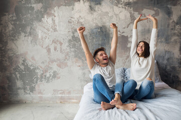 young happy smiling couple sitting on bed at home