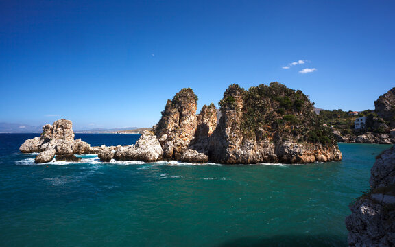 View across tranquil cove to the Faraglioni, Scopello