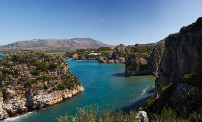 View across tranquil cove to the Faraglioni, Scopello