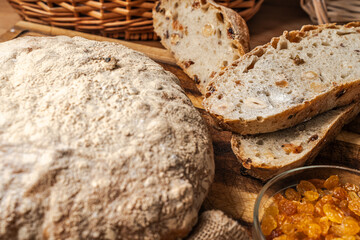 Bread with bran, nuts and raisins on a wooden board against the background of a wicker basket. Selected focus.