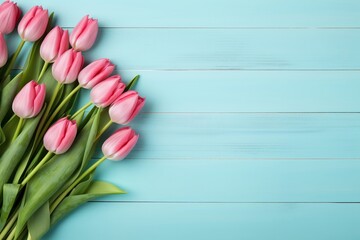 Fototapeta premium A beautiful arrangement of pink tulips on a light blue wooden background, perfect for spring themes, floral designs, or greeting cards.