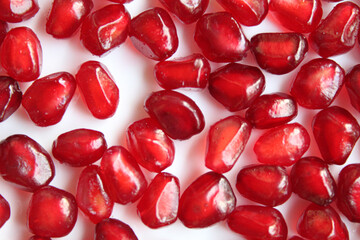 Spread of red flesh, pulp or seeds of pomegranate fruit, on white background