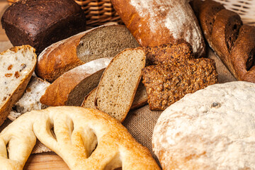 Various types of bread on a wooden table on a background of wicker baskets