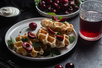 Viennese waffles with cherries on a dark background. Belgian waffles