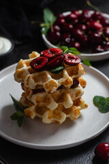 Viennese waffles with cherries on a dark background. Belgian waffles