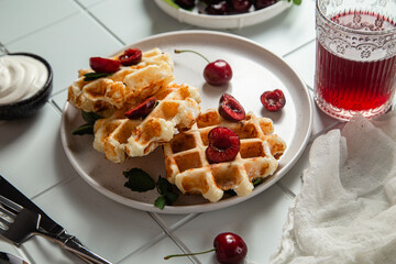 Viennese waffles with cherries on a dark background. Belgian waffles