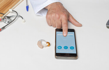 Doctor showing mobile application to adjust patient's hearing aids