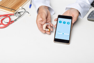 Audiologist showing smartphone application to make adjustments. Manage hearing aid settings via mobile app