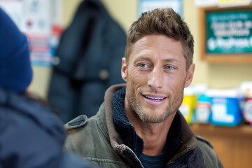 Obraz premium cheerful young man talking to a colleague in a shop