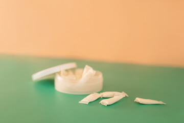 Plastic jar filled with white light snus sachets on a green background.