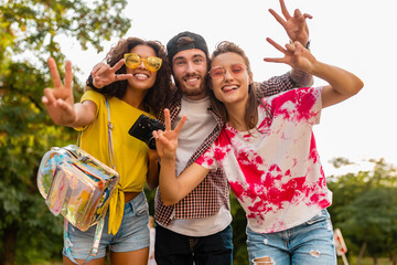 happy young company of emotional smiling friends walking in park