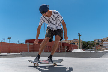 young skater wearing shorts does a trick with his skateboard in a skaterpark in a sunny day © magui RF