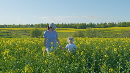 Fototapeta premium Happy Family Is Walking In Fresh Air. Portrait Of Mother With Son Having Fun In Yellow Field. Joy Family Lifestyle. Family Farmers. Real People.