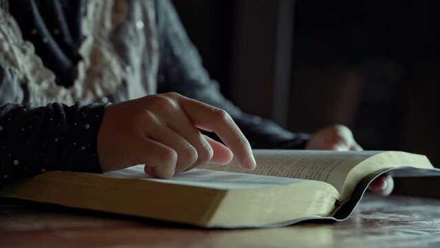 asian woman reading the Christian bible book on wooden table vintage room