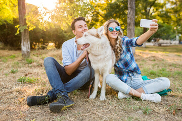 Fototapeta premium funny young stylish couple playing with dog in park