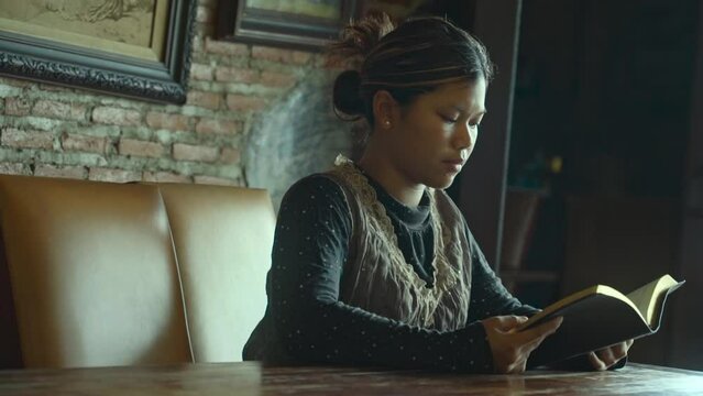 asian woman reading the Christian bible book on wooden table vintage room