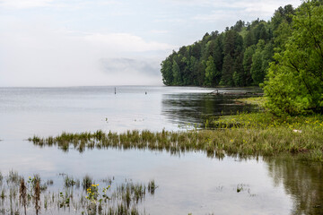 thick morning fog on the lake against the backdrop of mountains landscape on Lake Teletskoye