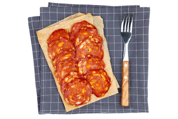 Chorizo salami slices on a napkin with a fork isolated on white