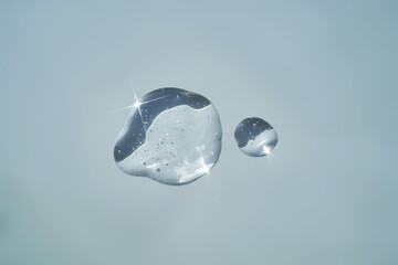 Drop of serum shimmering in the sun on a blue background.