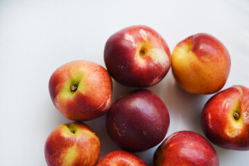 Red and yellow plums on a white background.