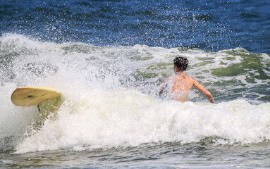 Boy falling off his surboard while surfing at Gigo Beach