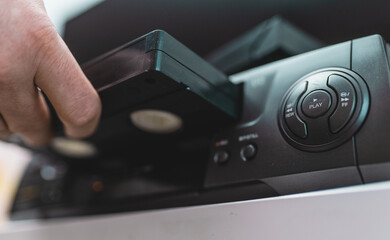 Close up of a hand holding a videotape. Retro vhs cassete in a player.	