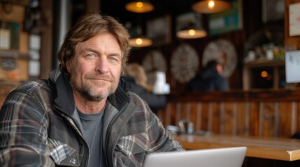 Fototapeta premium A focused entrepreneur with a determined look is working on a laptop in a cozy cafe. The warm ambient lighting creates a relaxed yet productive atmosphere.