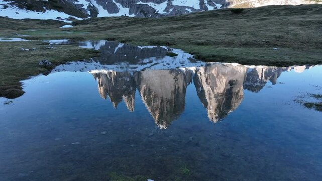 Snowy peaks of Tre Cime di Lavaredo in Italy mirrored in serene mountain lake waters in the Alps.