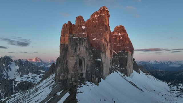 Drone captures the sunrise over the snow-covered Tre Cime di Lavaredo mountain range in South Tyrol.