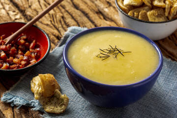 Delicious cassava cream (Caldo ou Creme de Mandioca) or cassava soup, typical of Brazilian cuisine, served in a blue porcelain bowl, on top of a typical rustic farm table, top view with selective focu