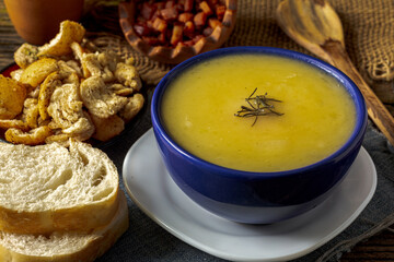 Delicious cassava cream (Caldo ou Creme de Mandioca) or cassava soup, typical of Brazilian cuisine, served in a blue porcelain bowl, on top of a typical rustic farm table, top view with selective focu