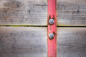 Screws on red painted bracket mounted to wood planks.