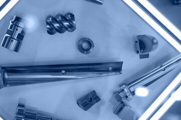 Metal products from CNC machine, parts blade of turbine, extruder, spiral guides. Industrial background blue toning, concept fix service