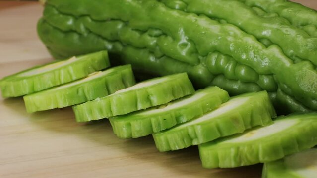 A bitter gourd, a vegetable often used as an ingredient in cuisine, is placed on a wooden table. This terrestrial plant is commonly found in various dishes and is known