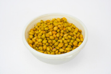 Dried coriander seeds in white bowl with close-up shot, isolated in white background